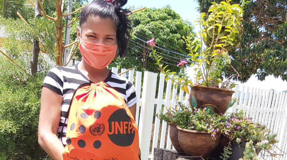 A pregnant woman with a UNFPA dignity kit wears a mask.