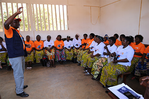 A doctor explains infection prevention protocols to a room of health care workers.