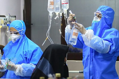 A health care worker fixes an IV line for a COVID-19 patient. 