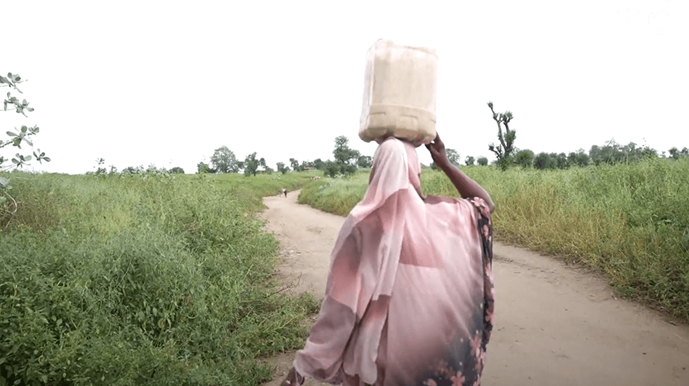 Woman carries grain from a flour mill in Sudan