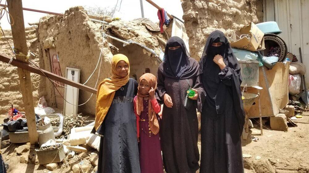 Souad and her children stand in front of what remains of their shelter in the Al Rawda displacement camp in Sa’ada Governorate, Yemen after a climate change-induced flood.