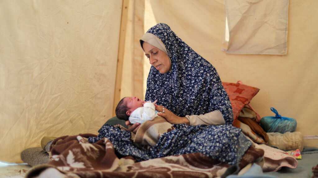 A displaced mother holds her newborn in Gaza.