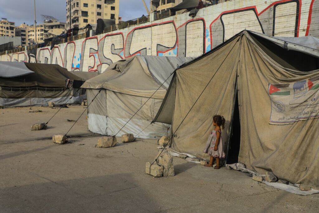 A girl stands at the entrance of her family’s tent in a displacement camp in western Gaza City